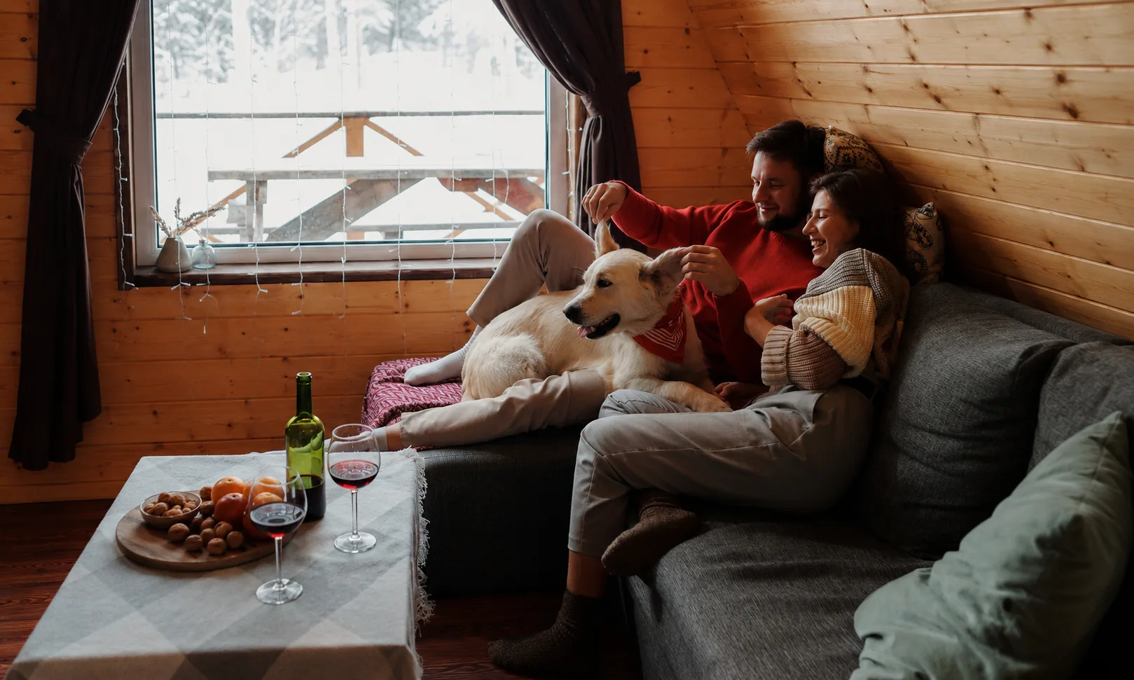 Paar mit Hund in einer gemütlichen Winterhütte an Silvester